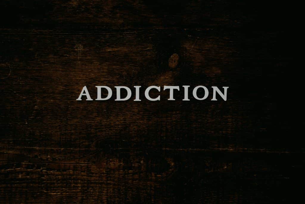 Word addiction written on bar wood indicating first stages of alcohol addiction.